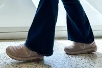 A person walking while wearing Vionic Women's Walk Strider Sneakers and jeans
