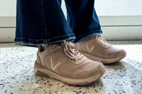 A person wearing the Vionic Women's Walk Strider Sneaker standing on a colorful floor