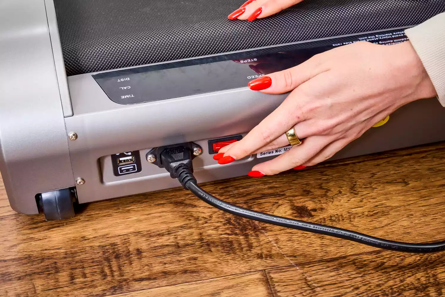 A hand pressing a button on the Egofit Walker Pro-M1 Treadmill