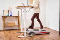 A person using a laptop while walking on the Egofit Walker Pro-M1 Treadmill