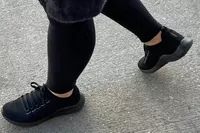 A person walks outside while wearing the Aetrex Carly Arch Support Sneakers