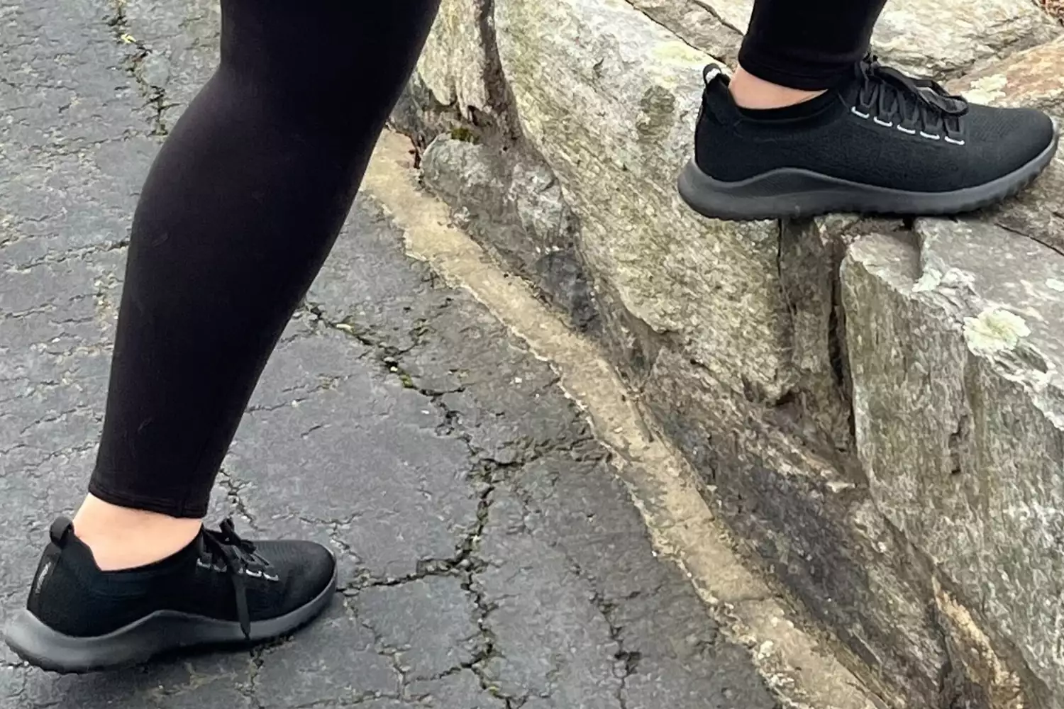 A person walks on stone while wearing the Aetrex Carly Arch Support Sneakers