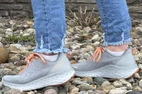 A person walks over pebbles while wearing the Aetrex Danika Arch Support Sneaker