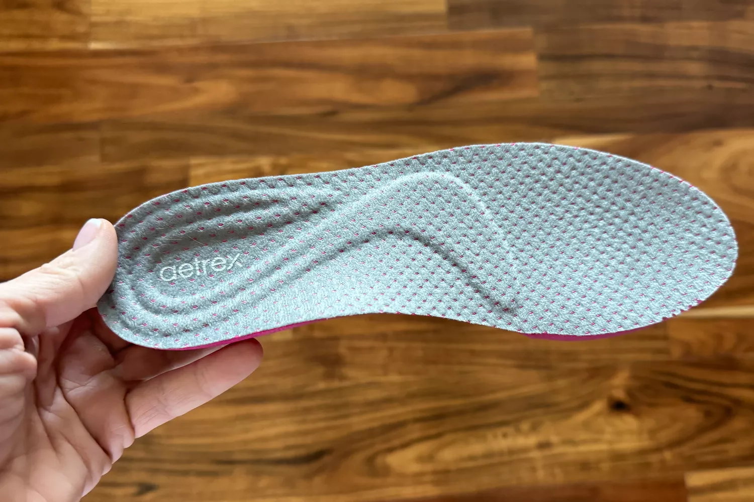 A person holds up the insole for the Aetrex Danika Arch Support Sneaker