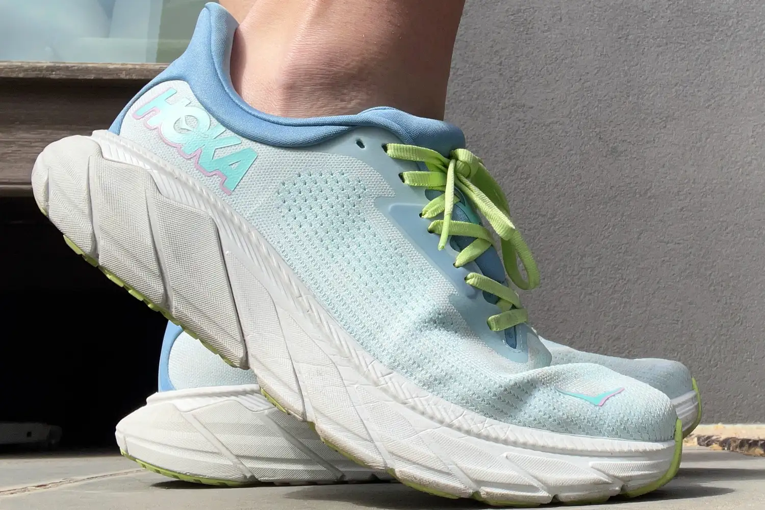A person shoes the side of the Hoka Womenâs Arahi 7 while standing