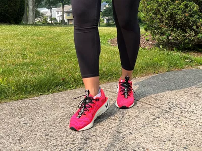 Feet wearing Nike Motiva Women's Walking Shoes on pavement