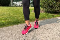 Feet wearing Nike Motiva Women's Walking Shoes on pavement
