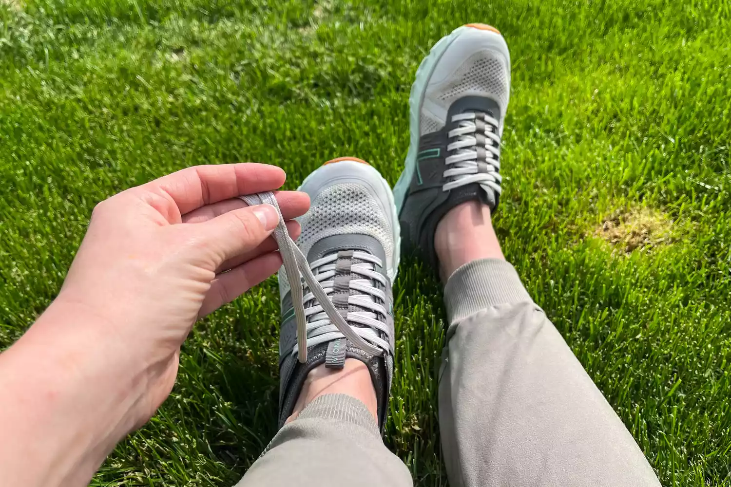 A hand holding an unties shoelace from a Vionic Captivate sneaker