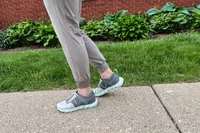 A close-up of a person wearing the Vionic Captivate sneaker on a sidewalk
