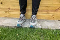 A person stands on concrete while wearing the Hoka Men's Kaha 2 Low GTX Hiking Shoes