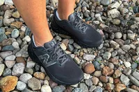 A person wears the New Balance Women's Fresh Foam Arishi v4 GTX Running Shoes while standing on pebbles
