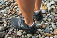 A person wears the New Balance Women's Fresh Foam Arishi v4 GTX Running Shoes while standing in pebbles