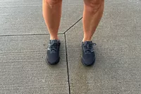 A person stands in concrete wearing the New Balance Women's Fresh Foam Arishi v4 GTX Running Shoes