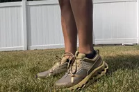 A person stands in grass while wearing the On Running Women's Cloudhorizon Waterproof Running Shoes