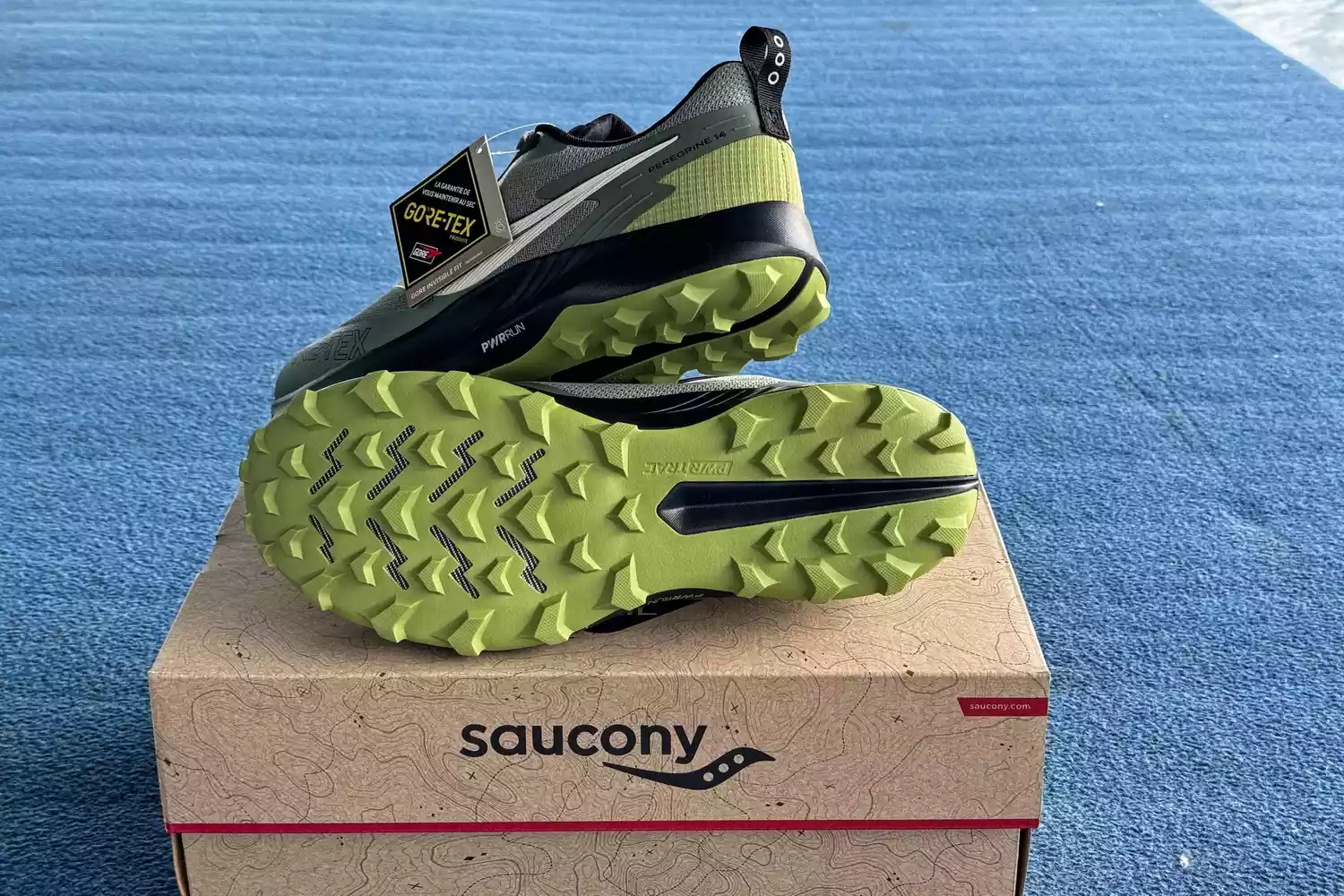 The treads on the bottom of the Saucony Men's Peregrine 14 GTX Waterproof Running Shoe on a shoebox