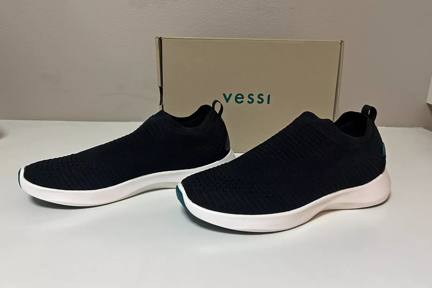 A pair of Vessi Men's Everyday Move Slip Ons in front of a shoebox