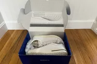 An open box on a wooden floor containing Birkenstock Bend Low Leather Sneakers