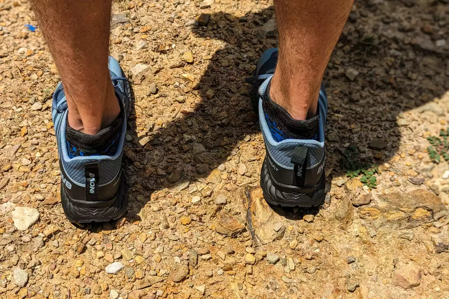 A person stepping on gravel while wearing the Inov8 Menâs TrailFly