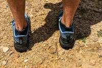 A person stepping on gravel while wearing the Inov8 Menâs TrailFly