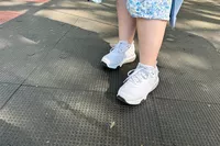 A person wearing MBT Womenâs Sport 4 II on a black textured background