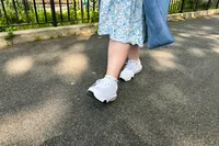 A person walking on blacktop in the MBT Womenâs Sport 4 II shoes