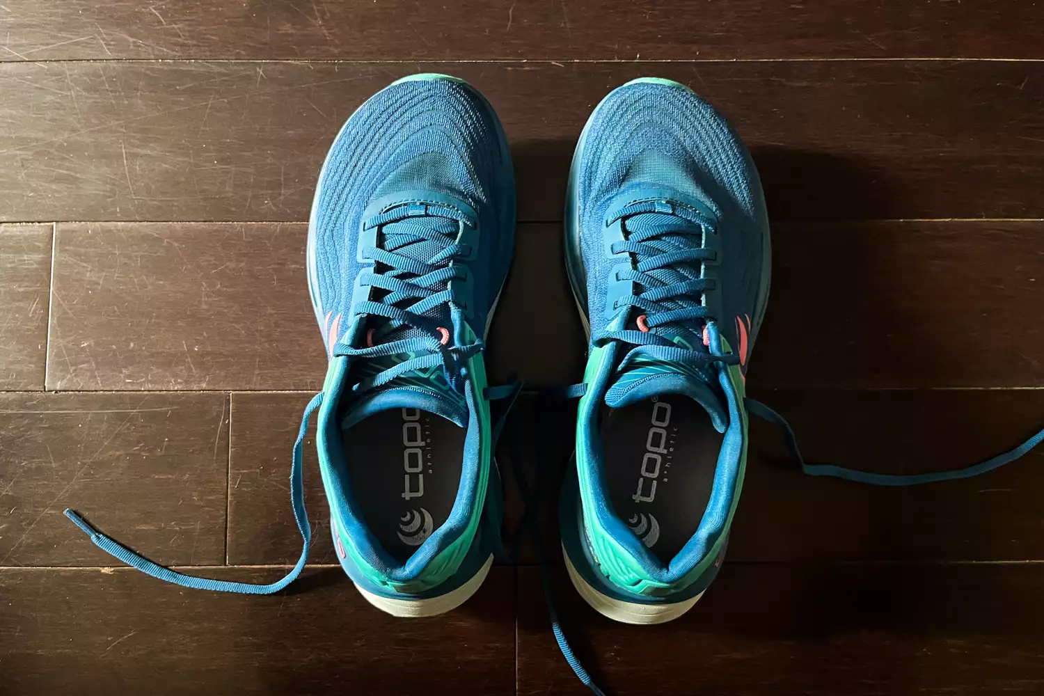 A top-view of the Topo Athletic Womenâs Ultrafly 5 shoes on a wooden floor