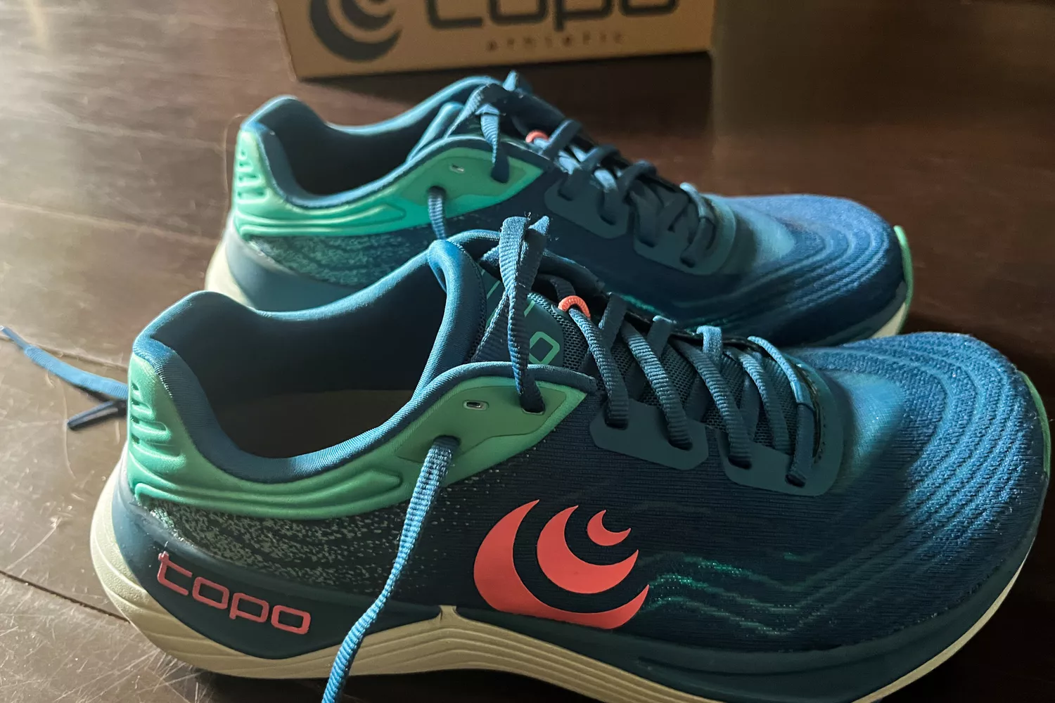 The Topo Athletic Womenâs Ultrafly 5 shoes on a wooden floor