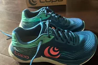 The Topo Athletic Womenâs Ultrafly 5 shoes on a wooden floor