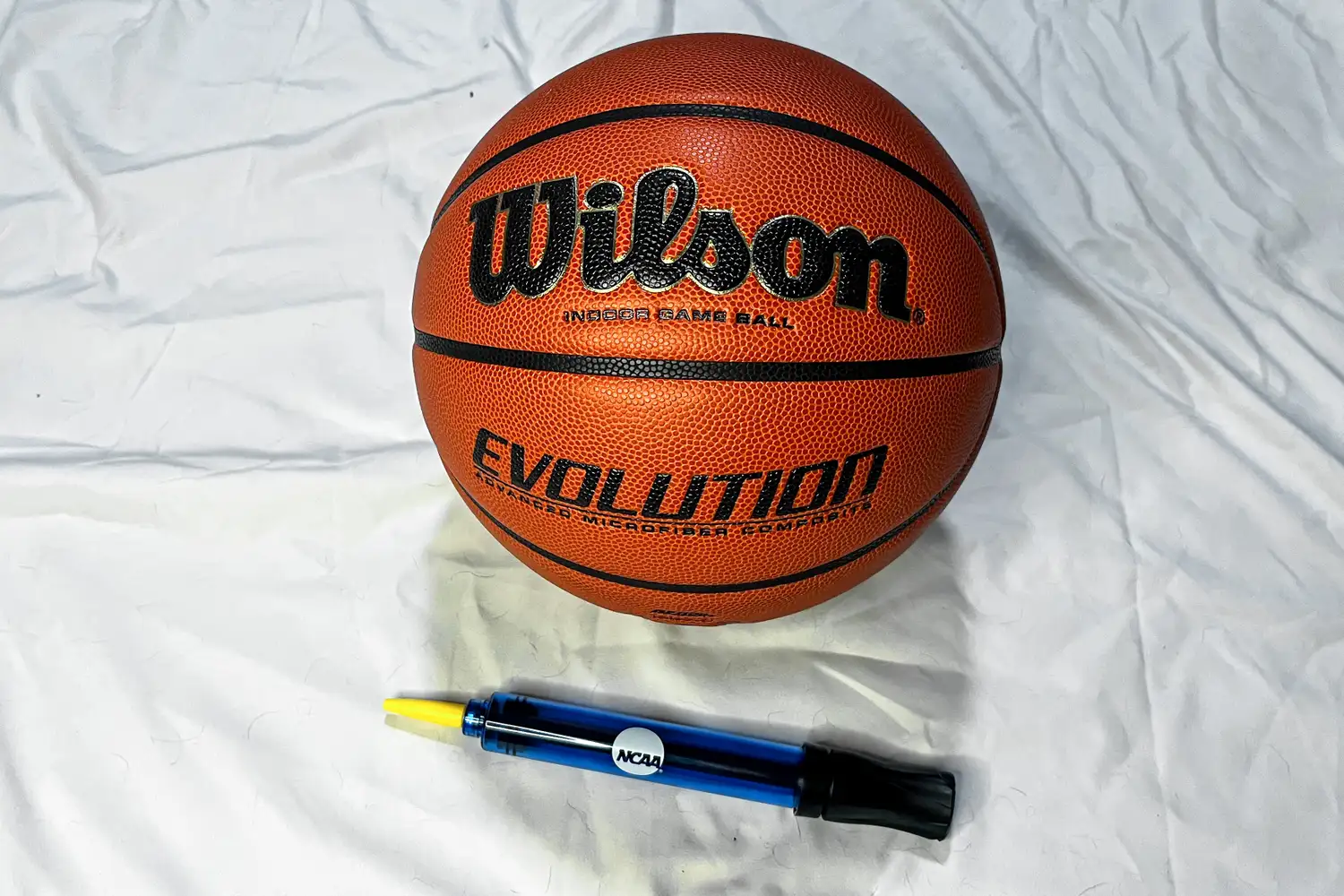 The Wilson Evolution Game Basketball next to an air pump
