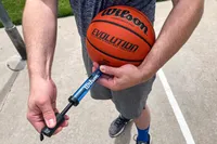 A person pumps air into the Wilson Evolution Game Basketball