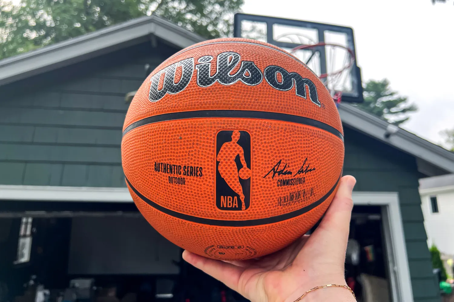 A person holds up the Wilson NBA Authentic Outdoor Basketball