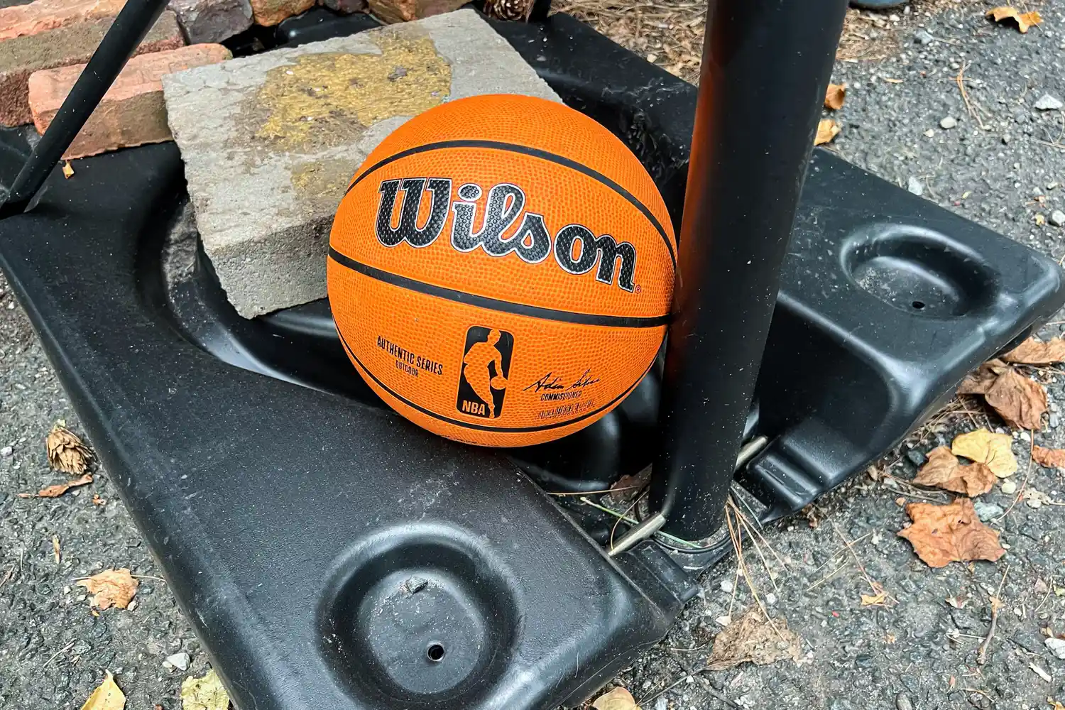 The Wilson NBA Authentic Outdoor Basketball on a basketball hoop base