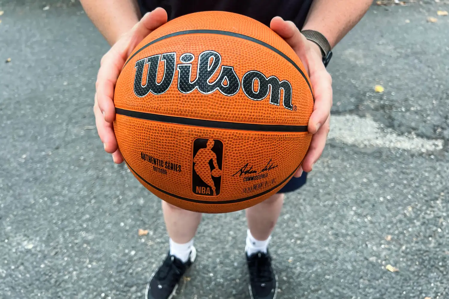 A person holds the Wilson NBA Authentic Outdoor Basketball