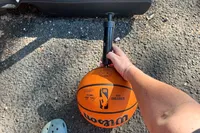 A person puts air in the Wilson NBA Authentic Outdoor Basketball