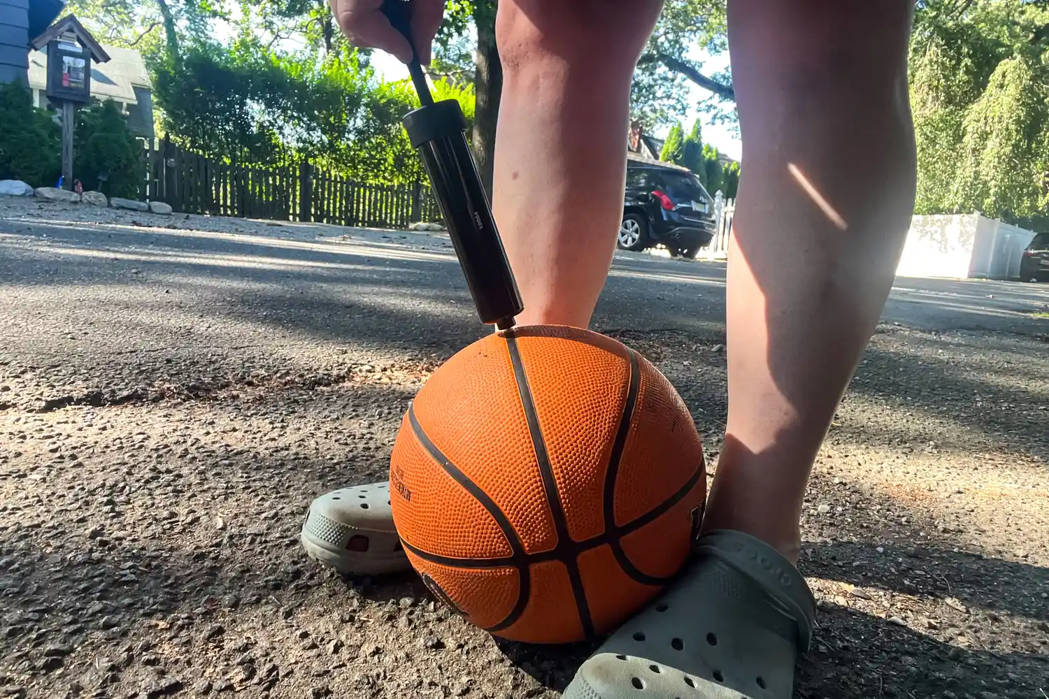 A person pumps air into the Wilson NBA Authentic Outdoor Basketball
