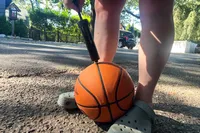 A person pumps air into the Wilson NBA Authentic Outdoor Basketball