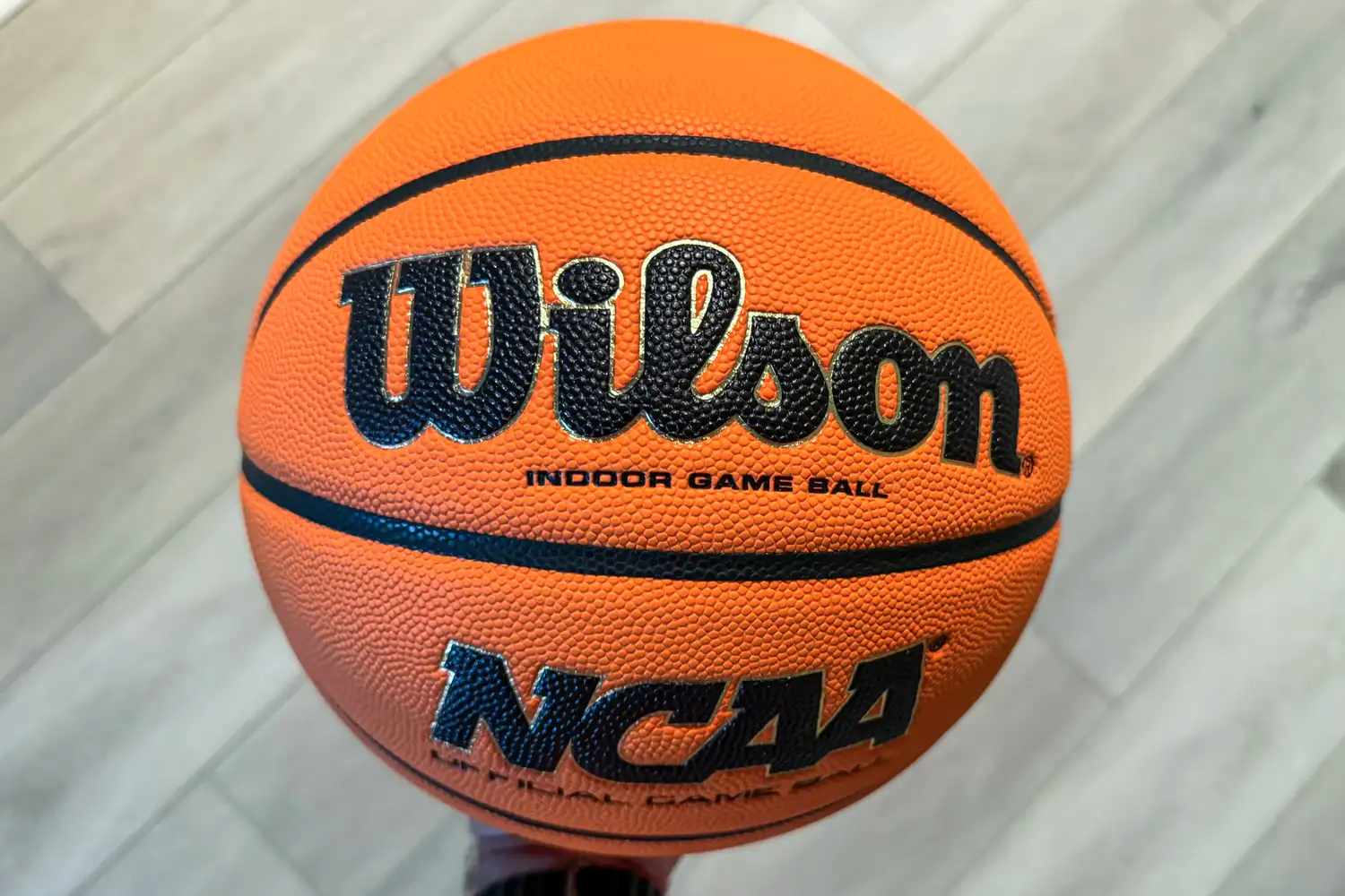 A person holds up the Wilson NCAA Evo NXT Game Basketball