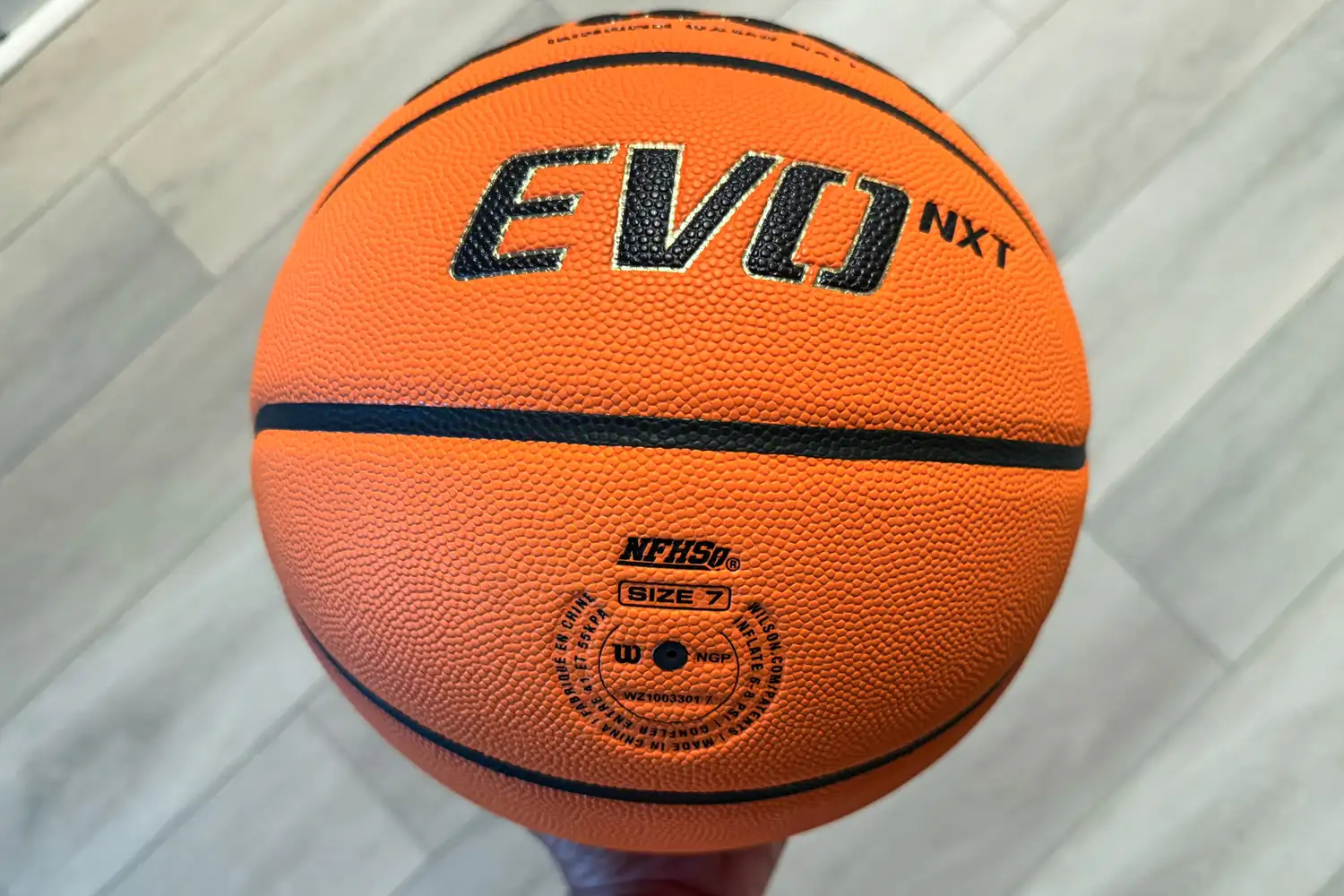 A person holds the Wilson NCAA Evo NXT Game Basketball