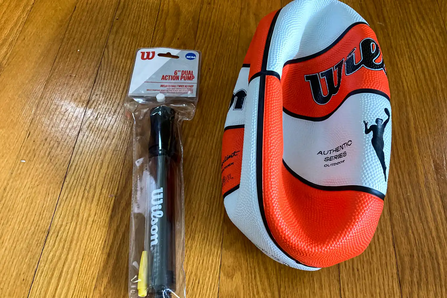 The Wilson WNBA Authentic Outdoor Basketball next to an air pump