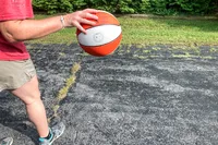 A person dribbles the Wilson WNBA Authentic Outdoor Basketball