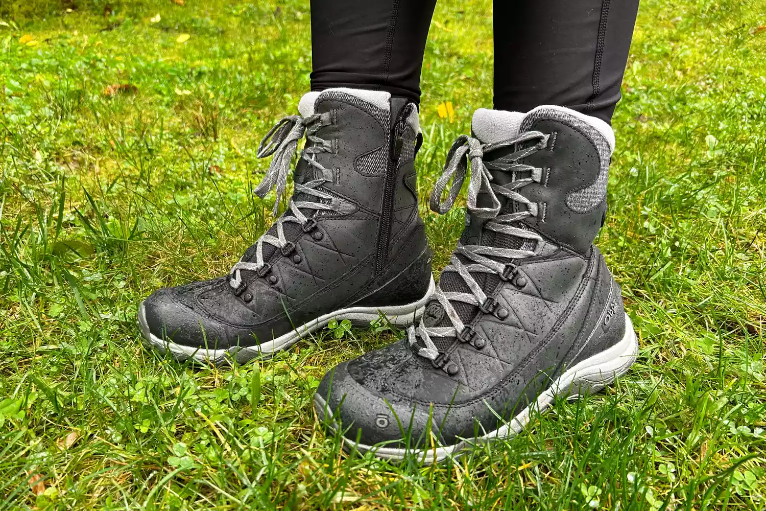A person wears the Oboz Ousel Mid Insulated Waterproof Boots in grass