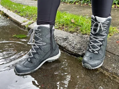 Closeup of waterproof hiking boots standing in a puddle.