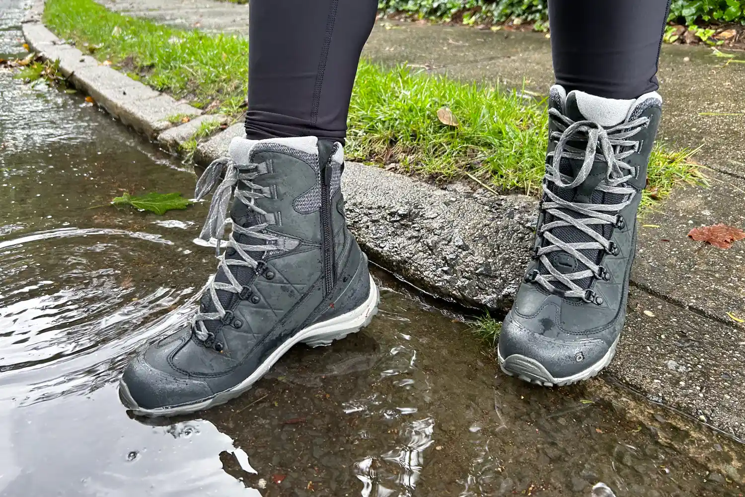 Closeup of waterproof hiking boots standing in a puddle.