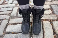 A person wears a pair of UGG Adirondack III Boots on a brick patio