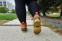 A person walks while wearing the L.L. Bean Women's 6in Bean Boots