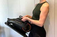 A person holds up the YOSUDA E5 Under Desk Elliptical Machine