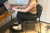 A side view of a person using the YOSUDA E5 Under Desk Elliptical Machine while sitting at a desk