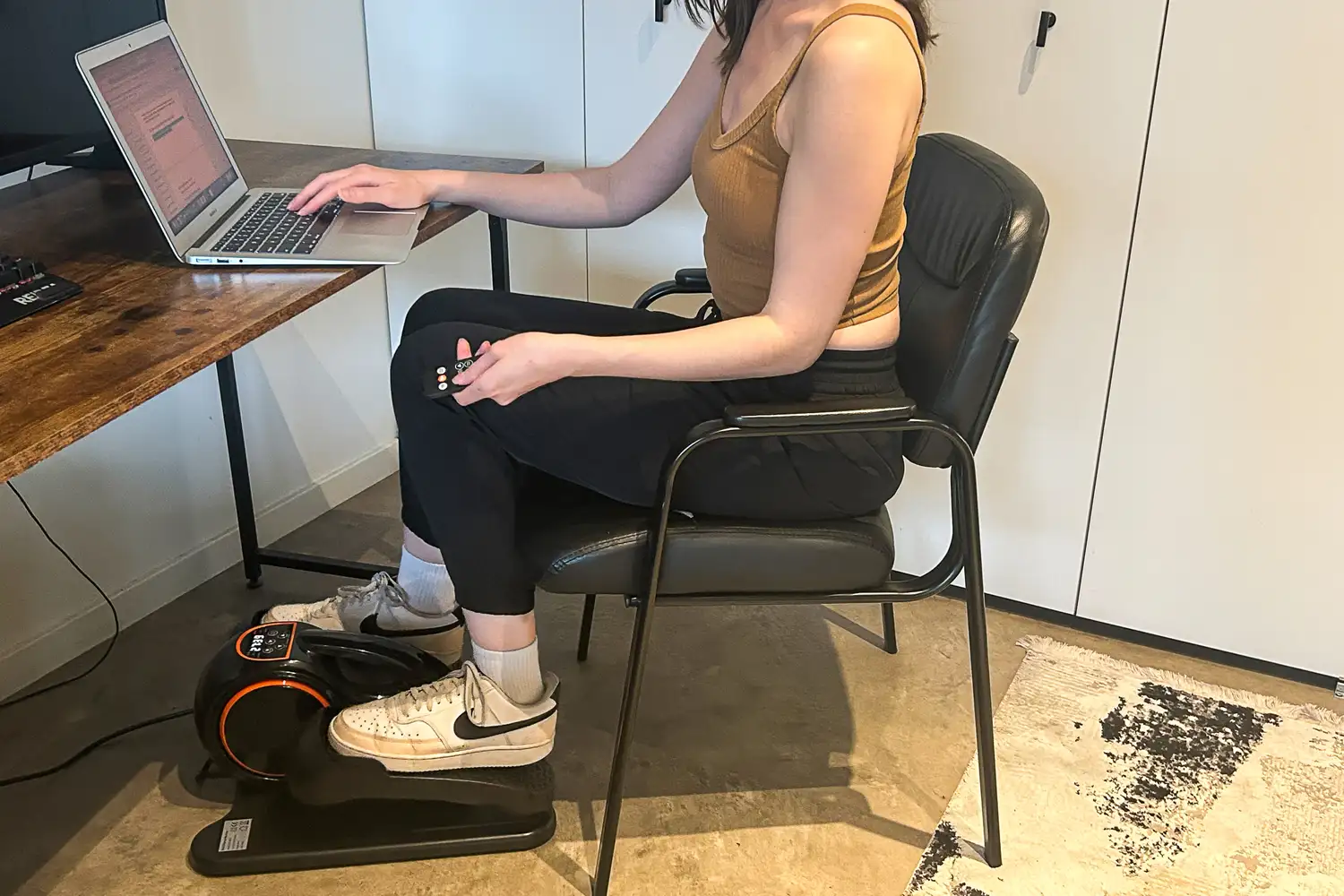 A person exercises on the YOSUDA E5 Under Desk Elliptical Machine while sitting in a chair