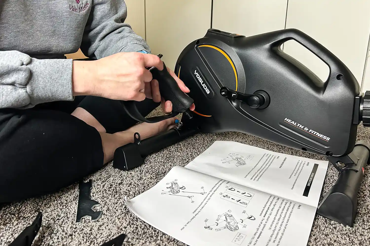 A person assembles the YOSUDA YBM-2 Under Desk Bike Pedal Exerciser