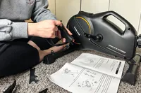 A person assembles the YOSUDA YBM-2 Under Desk Bike Pedal Exerciser